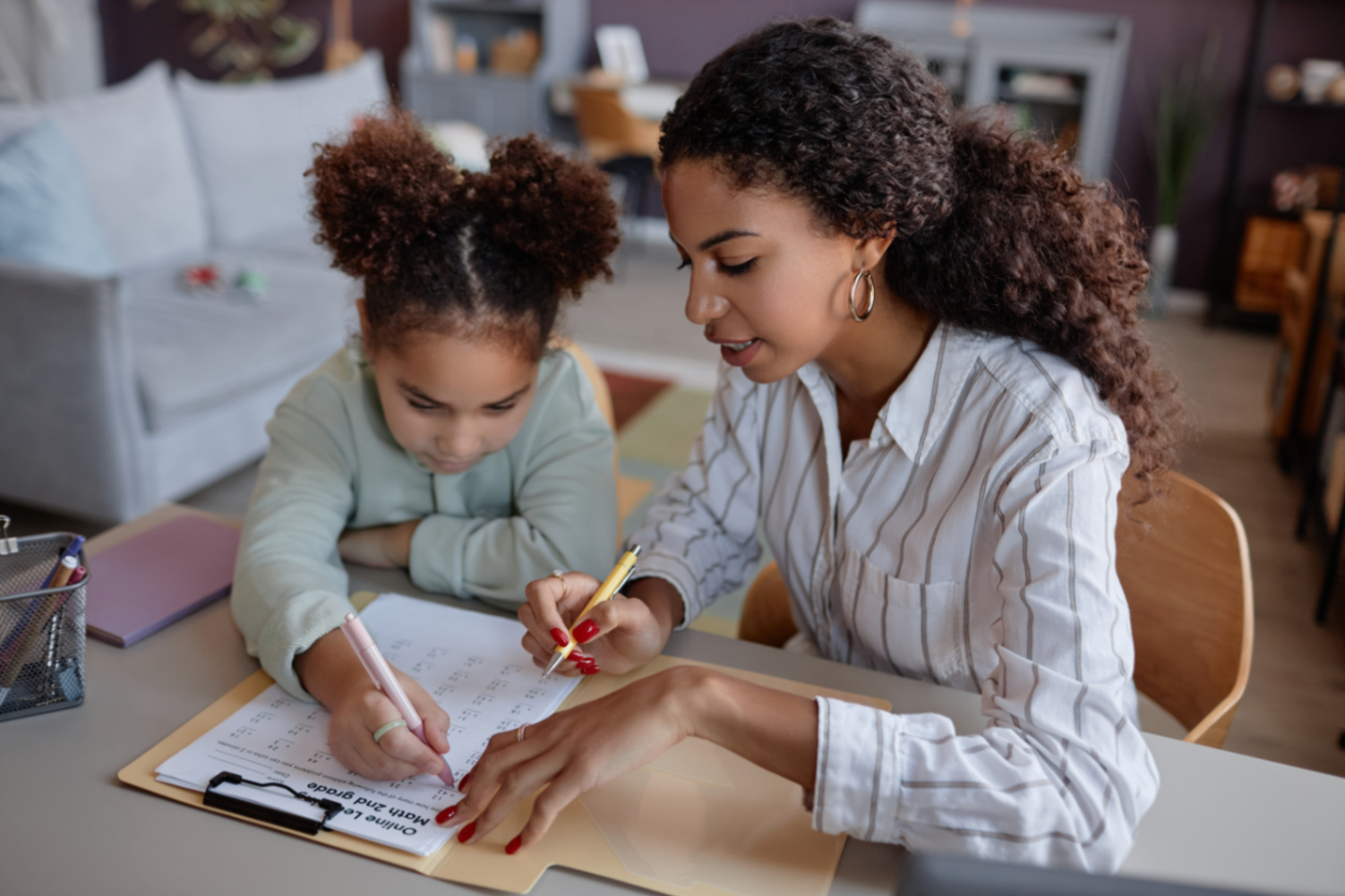 Black young woman explaining math to little girl